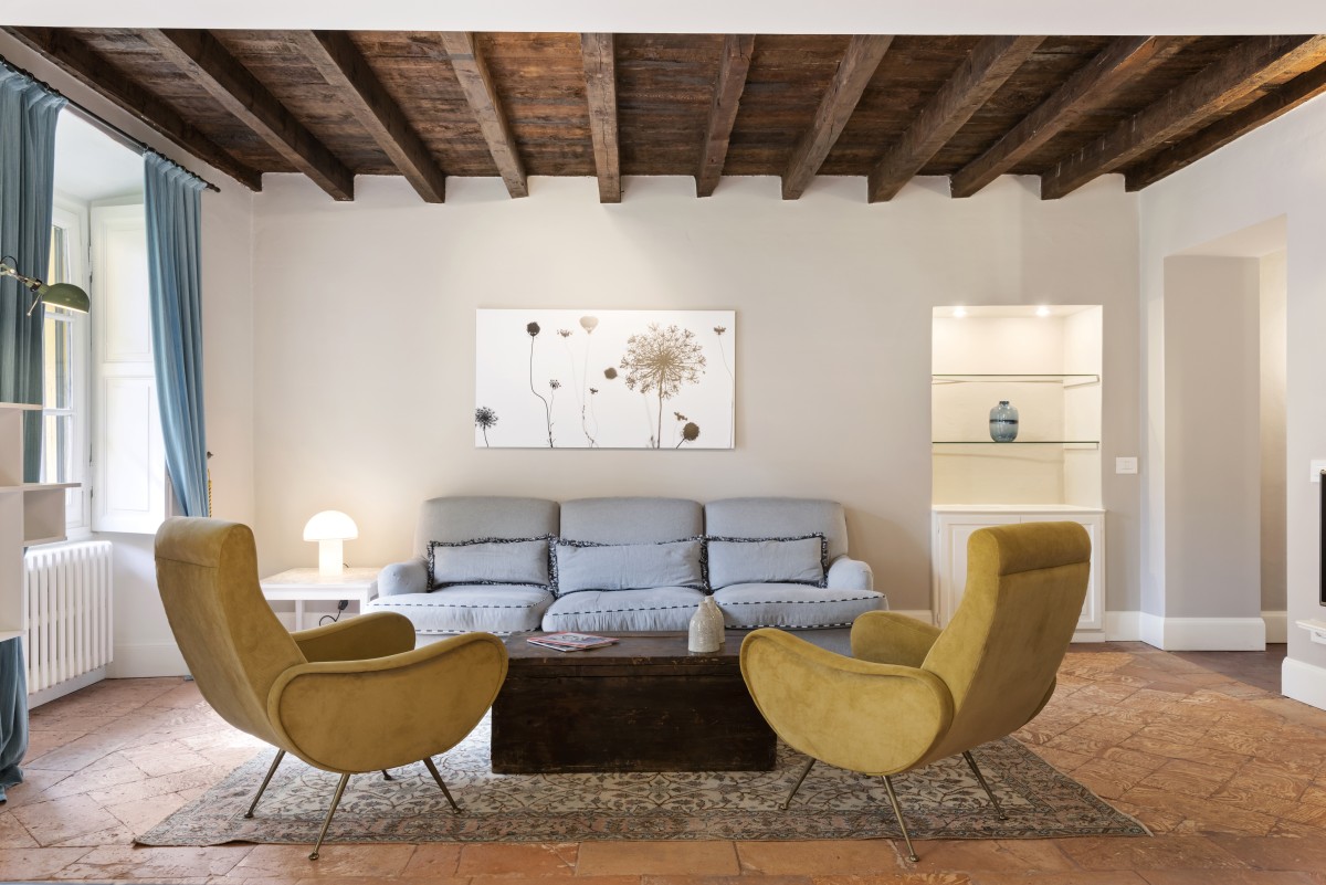 Salotto elegante con poltrone gialle, divano e travi in legno